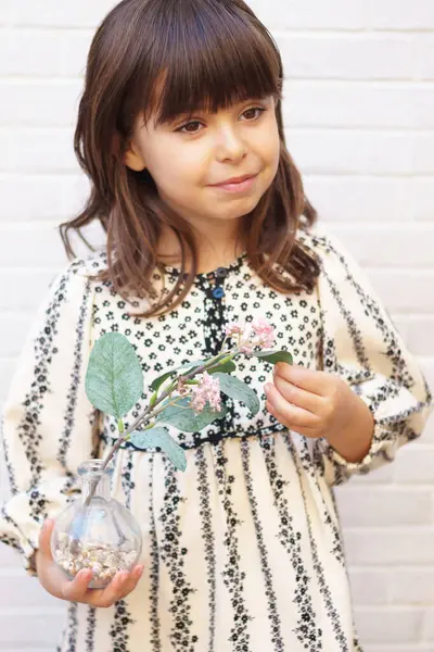 Elinde çiçekle gülümseyen 6 yaşındaki beyaz bir kızın portresi. Bahar konsepti Dikey.