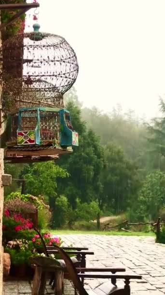 Regenachtige Dag Een Tuin Met Stoelen Bloemen Een Mooie Vogelkooi — Stockvideo