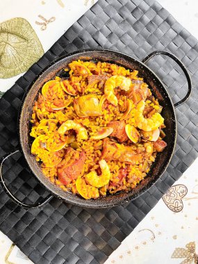 Ev yapımı tavuk ve İspanyol paella 'sı siyah masa örtüsü üzerinde. Düşük açı. Dikey çekim.