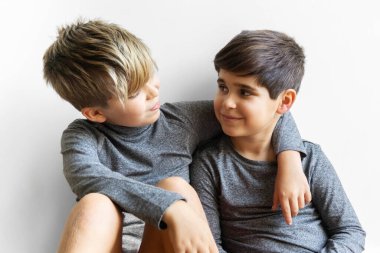 İki kardeş, 10 ve 8 yaşındalar, sarılırken birbirlerine bakıyorlar. Sevgi ve kardeşlik kavramı.