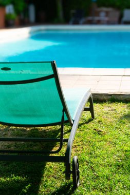 Yeşil güneşli yatak bir tatil evinin havuzunun yanında dinlenmeye davet ediliyor.
