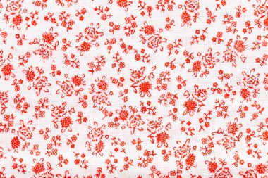 Beyaz keten kumaşa basılmış kırmızı çiçek deseni zarif ve büyüleyici bir tasarım oluşturuyor.