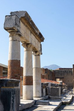 Pompeii 'de yükselen antik Roma sütunları ve arka planda beliren Vezüv Dağı