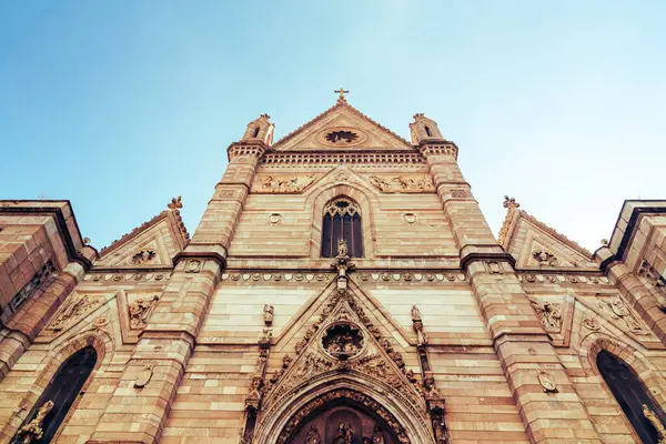 Napoli, İtalya 'daki Napoli katedralinin zengin cepheli cephesinin düşük açılı görüntüsü mavi gökyüzüne karşı karmaşık detaylarını gözler önüne seriyor.