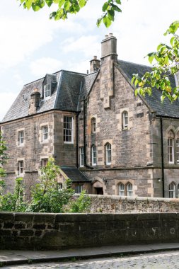 Dean Village, Edinburgh 'daki tarihi taş binaların manzarası, kaldırım taşı caddeleri ve yapraklı ağaçlar.