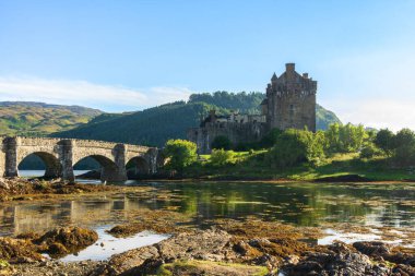 İskoçya 'daki güneşli bir günde, Eilean Donan Kalesi' nin anakaraya bağlayan tarihi köprüsü manzarası.