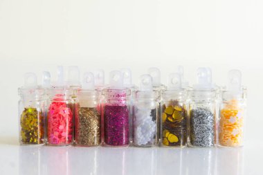 Renkli parıltı ve çeşitli şekillerde pullarla dolu bir sürü küçük cam kavanoz canlı bir düzenleme yaratıyor.