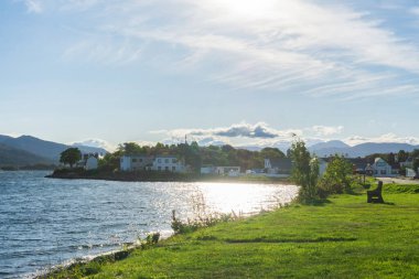 İskoçya Dağları 'ndaki Kyleakin Körfezi' nin sakin sularında parlayan güneş, arka planda dağlarla birlikte.