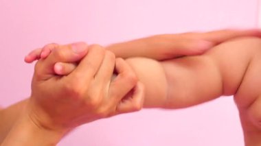 Yeni doğmuş bir bebeğin, pembe bir arka planda nazikçe el masajı yaptırdığı yakın plan. Yumuşak, rahatlatıcı hareketler sıcak ve şefkatli bir atmosfer yaratır. Sağlık ve ebeveynlik konuları için mükemmel.