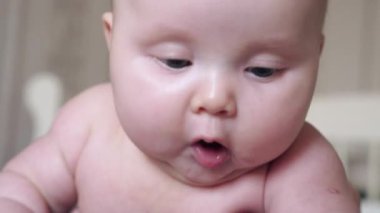 Meraklı bakışlı, ağzı sulanmış bir bebeğin yakın çekimi. Doğal ışıklandırma, ev ortamı, hassas duygular. Çocukluk, ebeveynlik ve bebek gelişimi konuları için mükemmel..