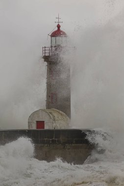 Dramatic seascape with big stormy waves splash over old lighthouse