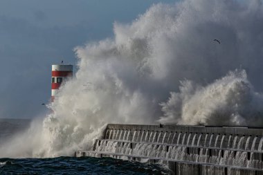 Büyük fırtınalı dalgalarla dramatik deniz manzarası. Kuzey Portekiz 'deki nehir ağzı rıhtımına ve deniz fenerine sıçrıyor..