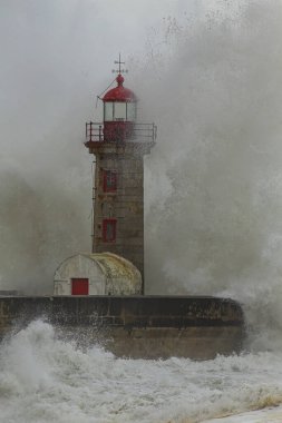 Dramatic seascape with big stormy waves splash over old lighthouse