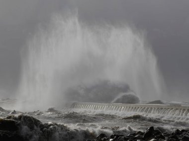 Douro nehri ağzı güney rıhtımı ve fener altında şiddetli fırtına altında Büyük çarpan dalgaların rüzgar spreyini görüyor Porto, Portekiz