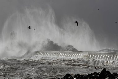 Douro nehri ağzı güney rıhtımı ve fener altında şiddetli fırtına altında Büyük çarpan dalgaların rüzgar spreyini görüyor Porto, Portekiz