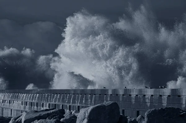 Big stormy wave splash at river mouth pier, north of Portugal. Used infrared filter. Toned blue.