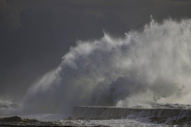 Büyük fırtınalı dalga sıçraması. Portekiz 'in kuzeyinde nehir ağzı iskelesi..