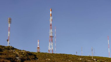 Kırmızı ve beyaz eski iletişim merkezi bir dağın tepesinden derin mavi gökyüzüne karşı