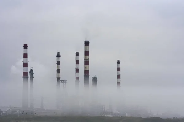 Old oil refinery in the middle of smog, steam and clouds