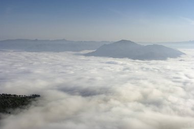 Şafak vakti puslu ve bulutlu yüksek dağ manzarası