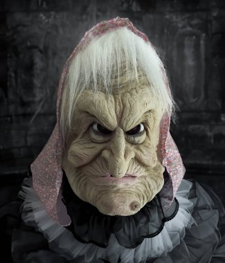 Karnaval ve cadılar bayramı maskeli yaşlı bir cadının karanlık arka planında çalıştı.