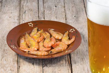 Geleneksel bir patates tabağında haşlanmış karides ve bir bardak bira.