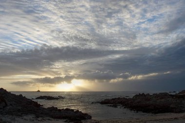 Gün batımında bulutlu deniz manzarası ufukta bir gemi görüyor.