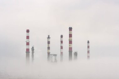 Sis, buhar ve bulutların ortasında eski petrol rafinerisi