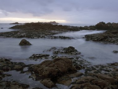 Kuzey Portekiz kayalık kıyıları alacakaranlıkta. Uzun pozlama.