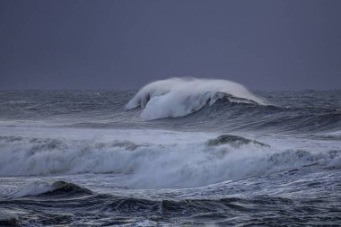 Alacakaranlıkta rüzgarla dalgalanan uzun deniz dalgaları.