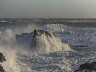 Portekiz 'in kuzeyindeki Labruge, S. Paio' nun kayalıkları, gün batımında dalgalı bir deniz günü..