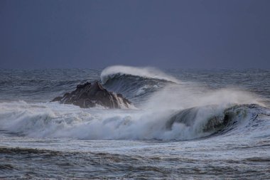 Akşam karanlığında fırtınalı deniz dalgaları. Kuzey Portekiz kıyıları.