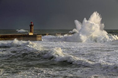 Nisan 'da Portekiz' de Douro, Porto, Portekiz 'in deniz feneri ve feneri üzerinde fırtına dalgaları başladı. Geç akşam ışığı (düşük basım fotoğraf)