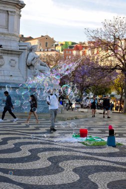 Sokak sanatçısı, Lizbon 'daki Rossio Meydanı' nın (Praa D. Pedro IV) ortasında yer alan D. Pedro IV Sütununda büyük sabun köpükleri yapıyor.