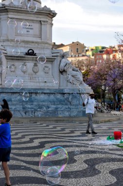 Sokak sanatçısı, Lizbon 'daki Rossio Meydanı' nın (Praa D. Pedro IV) ortasında yer alan D. Pedro IV Sütununda büyük sabun köpükleri yapıyor.