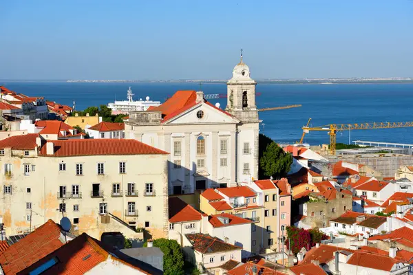 Lizbon, Portekiz 'in Alfama ilçesinin panoramik manzarası, önde Igreja de Santo Estvo (St. Stephen Kilisesi) ve arkada Tagus Nehri yer almaktadır.