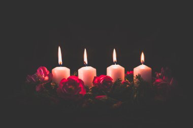 Madalyalı gül çiçeğinin dördüncü yanan mumu pembe renkli çelenk.