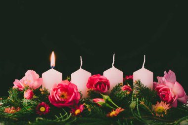 Süslü gül çiçeğinin ilk yanan mumu pembe bir çelenk.