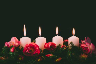 Madalyalı gül çiçeğinin dördüncü yanan mumu pembe renkli çelenk.