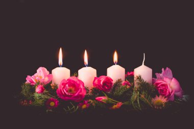 Madalyalı gül çiçeğinin üçüncü yanan mumu pembe renkli çelenk