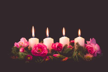 Madalyalı gül çiçeğinin dördüncü yanan mumu pembe renkli çelenk.