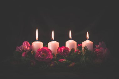 Madalyalı gül çiçeğinin dördüncü yanan mumu pembe renkli çelenk.