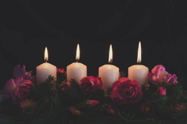 Madalyalı gül çiçeğinin dördüncü yanan mumu pembe renkli çelenk.