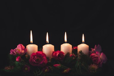 Madalyalı gül çiçeğinin dördüncü yanan mumu pembe renkli çelenk.