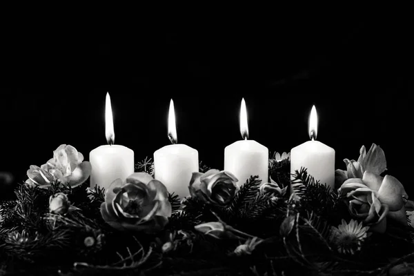 fourth burning advent candle on decorated rose flower monochrome advent wreath