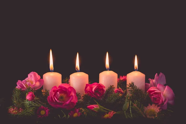 fourth burning advent candle on decorated rose flower pink advent wreath