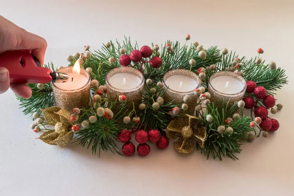 liting first candle, 4 golden advent candles in religious cristian traditional wreath decorated with green fir and baubles