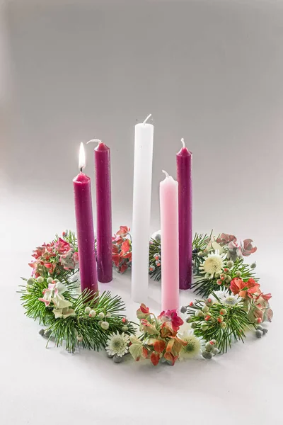3 purple candles, 1 pink and one white candle on decorated and adorned christian advent wreath, isolated, first advent week