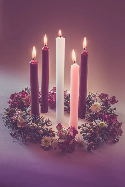 3支紫色的蜡烛 1支粉色的 1支白色的蜡烛 挂在装饰过的基督教花环上 与世隔绝 — 图库照片