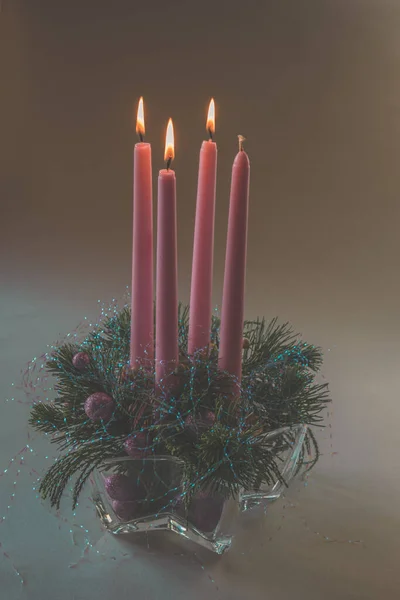 4 pink advent candles in religious cristian traditional wreath decorated with green fir and baubles